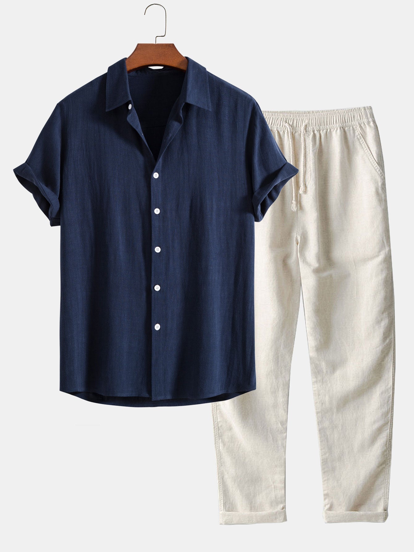Navy shirt and white pants on a hanger against a light gray background