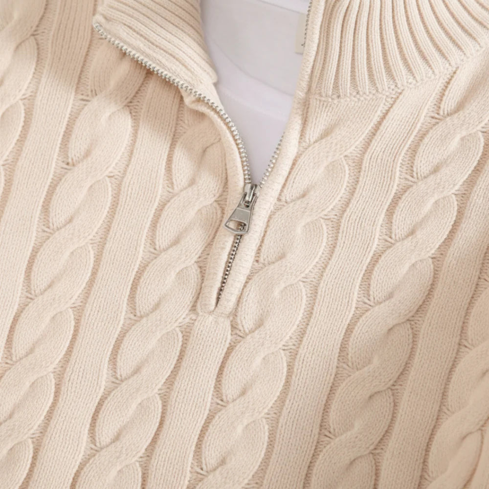 Close-up of a beige cable knit sweater with a zipper.