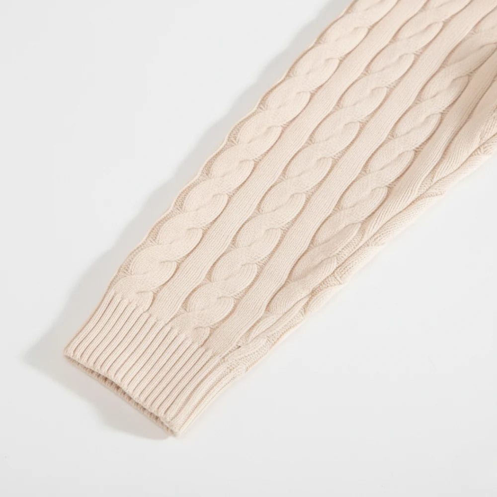 Beige cable knit sweater sleeve on a light gray background