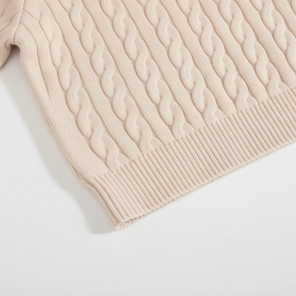 Close-up of a beige cable knit sweater on a white background
